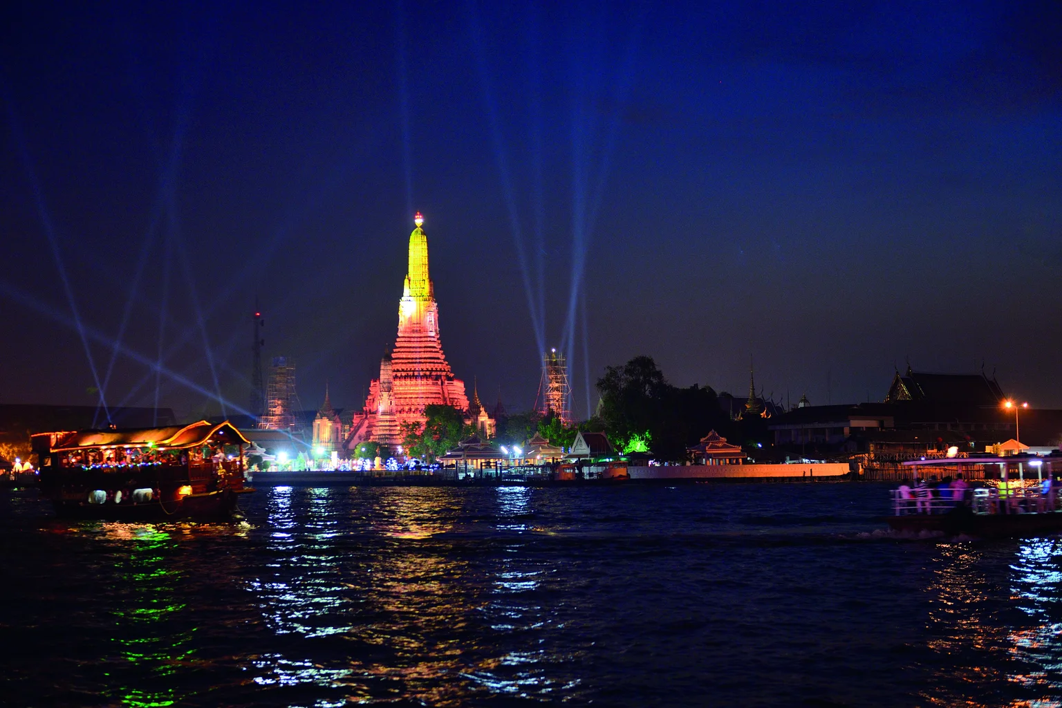 Wat Arun illuminated beside the Chao Phraya River in Bangkok at night